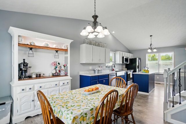 1627 Metcalfe Ave, Columbus, OH 43207 - dining area featuring a chandelier, light wood-type flooring, vaulted ceiling, and stairs
