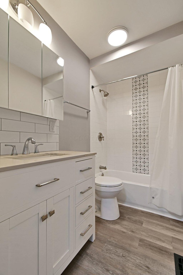 2567 Joyce Ave, Columbus, OH 43211 - full bathroom featuring shower / bath combination with curtain, vanity, toilet, tasteful backsplash, and wood finished floors