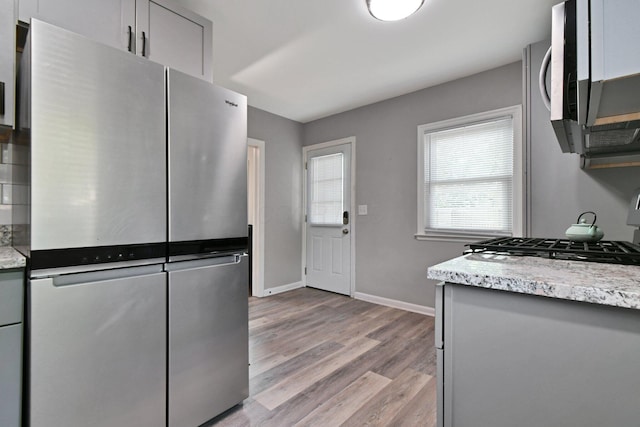 2567 Joyce Ave, Columbus, OH 43211 - kitchen with freestanding refrigerator, stove, baseboards, light wood-type flooring, and gray cabinetry