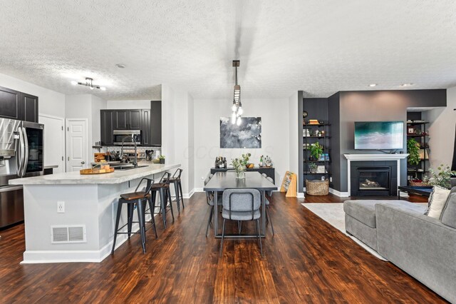 4006 Darby Park Rd, Hilliard, OH 43026 - kitchen featuring appliances with stainless steel finishes, dark wood finished floors, light countertops, a breakfast bar area, and dark cabinets