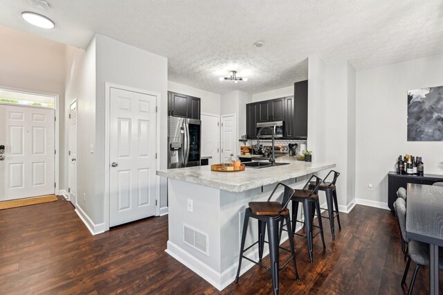 4006 Darby Park Rd, Hilliard, OH 43026 - kitchen featuring stainless steel appliances, dark cabinetry, a peninsula, dark wood-type flooring, and light countertops