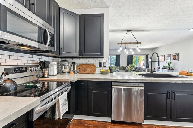 4006 Darby Park Rd, Hilliard, OH 43026 - kitchen featuring stainless steel appliances, a sink, backsplash, a textured ceiling, and dark cabinetry