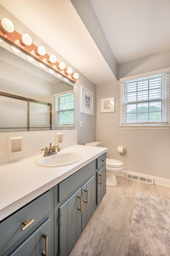 837 Cherry Bottom Rd, Columbus, OH 43230 - full bath with vanity, toilet, baseboards, wood finished floors, and a shower with door