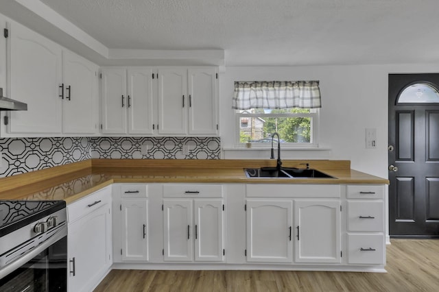 19616 N St, Laurelville, OH 43135 - kitchen with a sink, stainless steel range with gas cooktop, white cabinetry, light wood-type flooring, and wall chimney exhaust hood