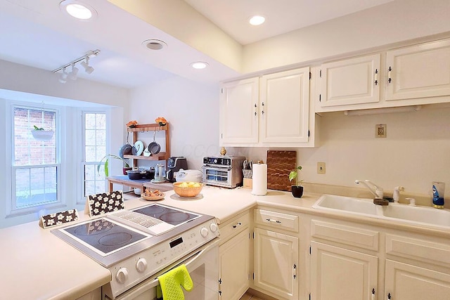 4760 Coach Rd Unit 14, Columbus, OH 43220 - kitchen featuring range, light countertops, a sink, track lighting, and white cabinetry