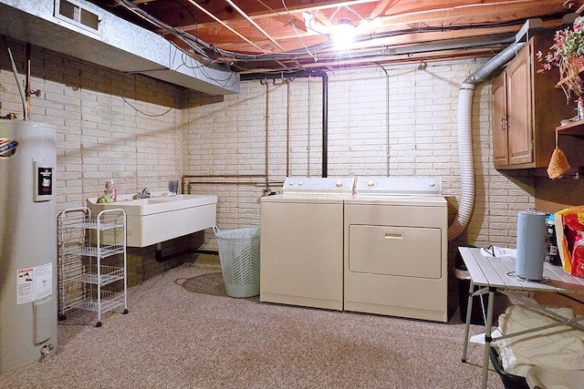 4760 Coach Rd Unit 14, Columbus, OH 43220 - laundry room featuring washing machine and dryer, water heater, cabinet space, brick wall, and light carpet