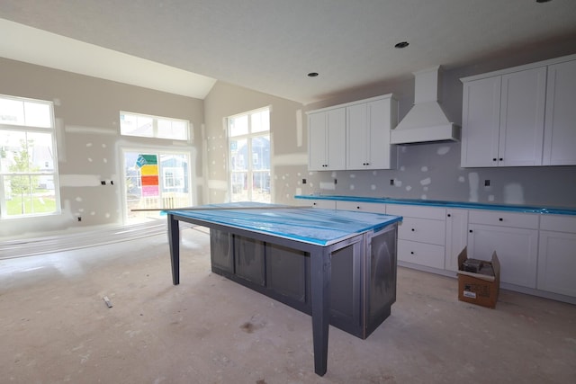 6946 Stillhouse Ln, Dublin, OH 43016 - kitchen featuring premium range hood, unfinished concrete floors, white cabinets, vaulted ceiling, and a kitchen island