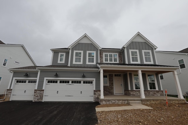 6946 Stillhouse Ln, Dublin, OH 43016 - view of front of home with covered porch, board and batten siding, driveway, and stone siding