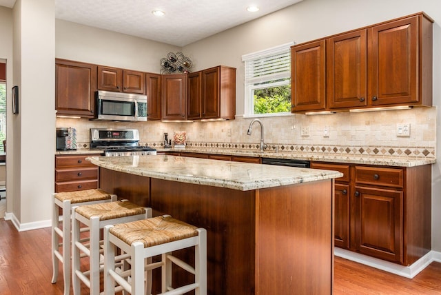2545 Bryton Dr, Powell, OH 43065 - kitchen featuring stainless steel appliances, light wood-style flooring, a sink, a breakfast bar, and a center island