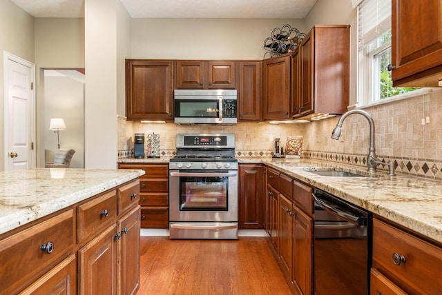 2545 Bryton Dr, Powell, OH 43065 - kitchen featuring appliances with stainless steel finishes, a sink, dark wood-type flooring, light stone countertops, and tasteful backsplash