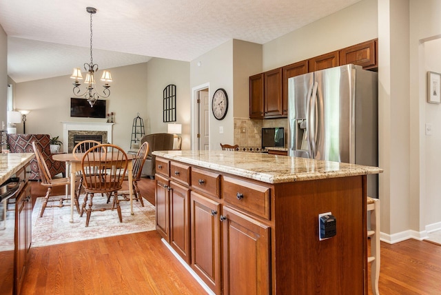 2545 Bryton Dr, Powell, OH 43065 - kitchen featuring stainless steel refrigerator with ice dispenser, light wood finished floors, decorative light fixtures, open floor plan, and a center island