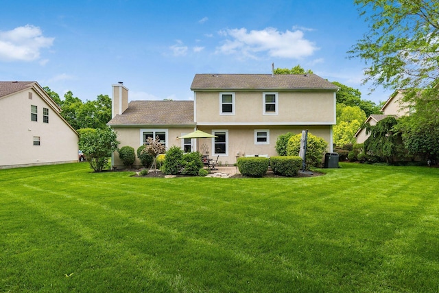 2545 Bryton Dr, Powell, OH 43065 - rear view of house featuring a yard, a patio, a chimney, and stucco siding