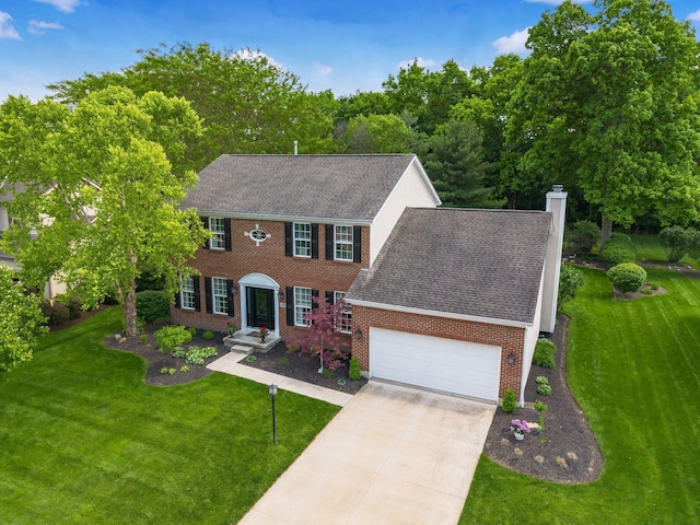 2545 Bryton Dr, Powell, OH 43065 - colonial house featuring brick siding, a chimney, a garage, a front yard, and driveway