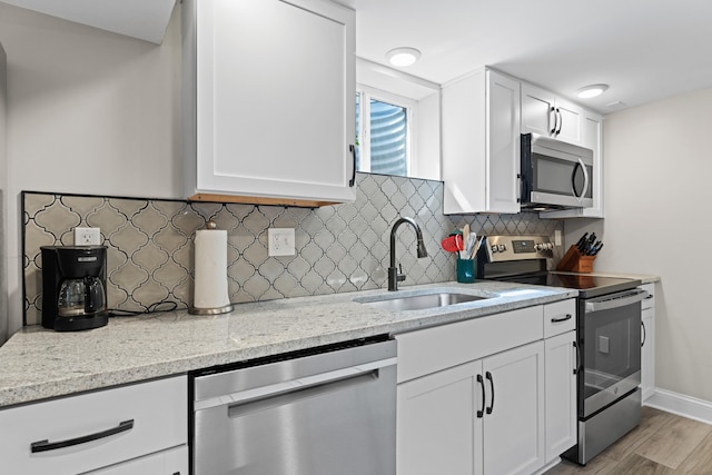 3531 Colchester Rd, Upper Arlington, OH 43221 - kitchen featuring appliances with stainless steel finishes, a sink, white cabinets, light stone counters, and light wood-type flooring