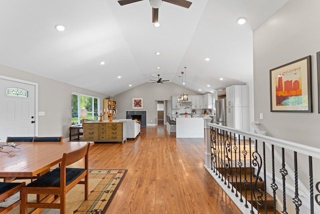 3531 Colchester Rd, Upper Arlington, OH 43221 - dining area with ceiling fan, a warm lit fireplace, lofted ceiling, light wood-style flooring, and baseboards
