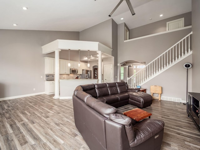 6868 Beltain Ln Unit 37B, Dublin, OH 43016 - living room with ornate columns, high vaulted ceiling, arched walkways, light wood-type flooring, and stairs