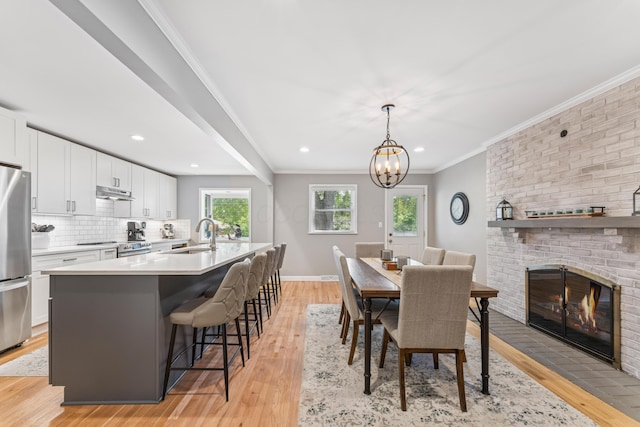 3985 Glenda Pl, Upper Arlington, OH 43220 - dining room featuring light wood finished floors, a chandelier, a fireplace, crown molding, and recessed lighting