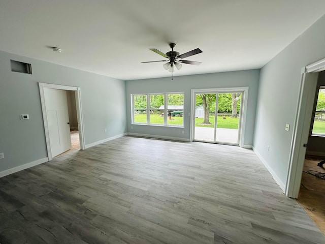 15848 Barnes Dr, Belle Center, OH 43310 - unfurnished living room featuring a ceiling fan, healthy amount of natural light, wood finished floors, and baseboards