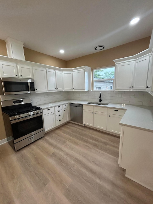 944 Binns Blvd, Columbus, OH 43204 - kitchen with stainless steel appliances, a sink, tasteful backsplash, light wood-style floors, and white cabinets