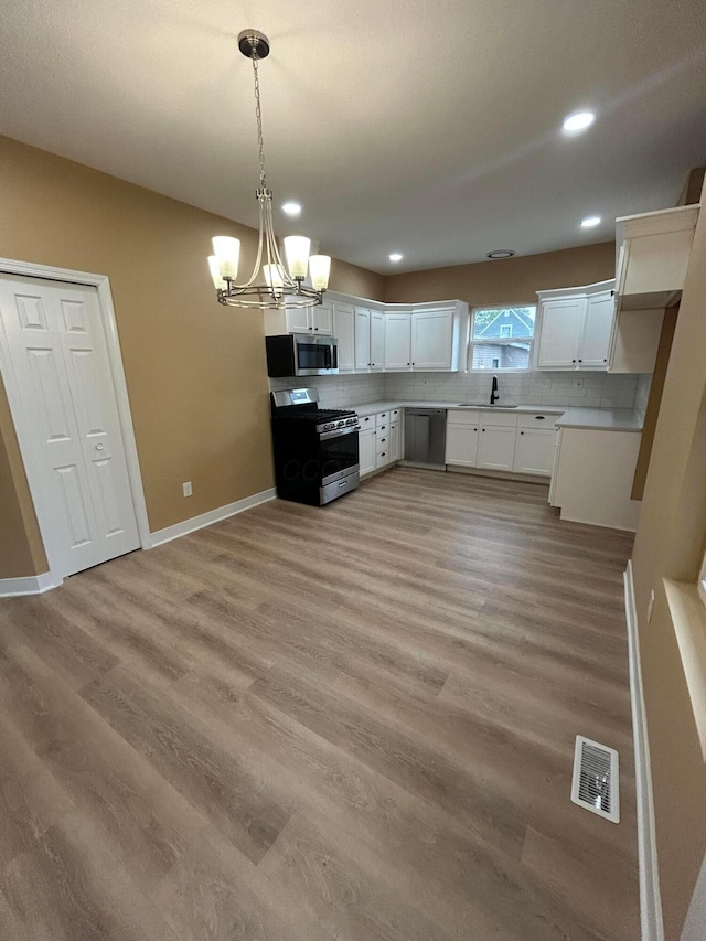 944 Binns Blvd, Columbus, OH 43204 - kitchen with stainless steel appliances, light wood-type flooring, a chandelier, decorative backsplash, and white cabinets