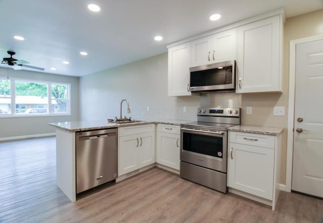 1541 Taft St, Marion, OH 43302 - kitchen with appliances with stainless steel finishes, a sink, a peninsula, light wood-type flooring, and white cabinets