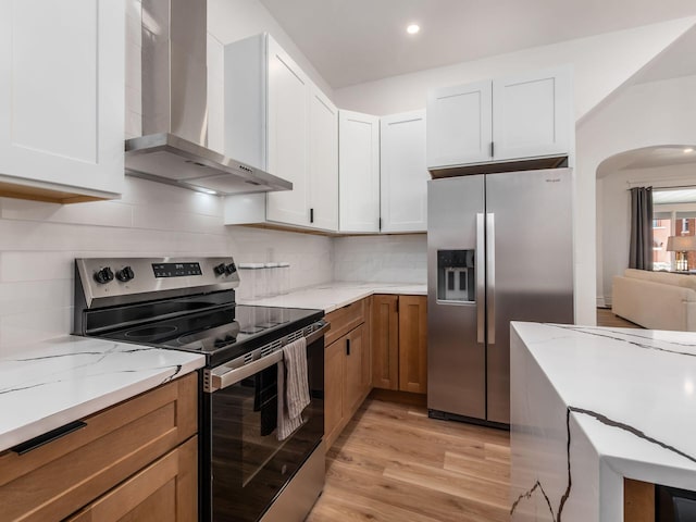 883 Wilson Ave, Columbus, OH 43206 - kitchen featuring wall chimney exhaust hood, stainless steel appliances, light wood-style floors, light stone counters, and tasteful backsplash