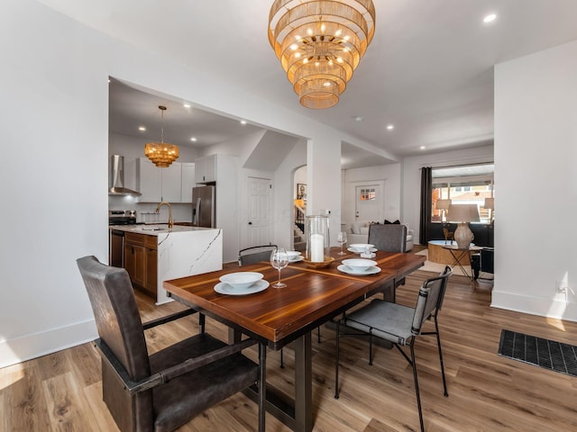 883 Wilson Ave, Columbus, OH 43206 - dining room with a chandelier, baseboards, light wood-style flooring, arched walkways, and recessed lighting