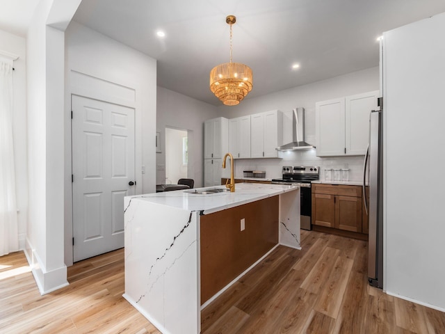 883 Wilson Ave, Columbus, OH 43206 - kitchen featuring stainless steel appliances, wall chimney range hood, a chandelier, light wood-type flooring, and tasteful backsplash