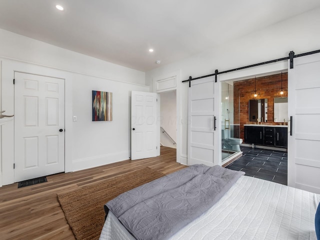 883 Wilson Ave, Columbus, OH 43206 - bedroom with a barn door, dark wood-style floors, baseboards, ensuite bathroom, and recessed lighting