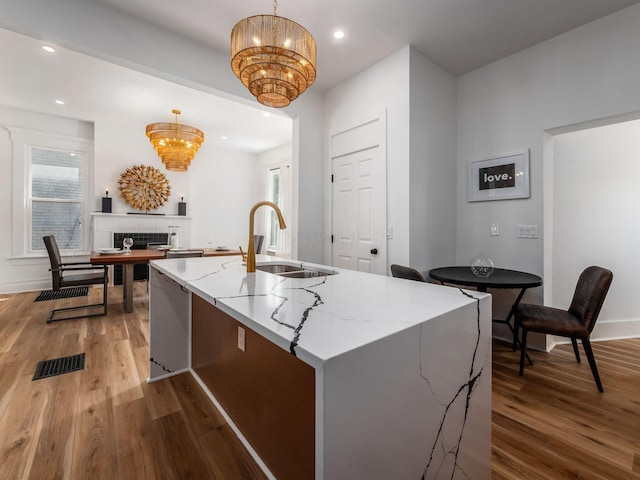 883 Wilson Ave, Columbus, OH 43206 - kitchen with a sink, a chandelier, wood finished floors, light stone counters, and recessed lighting