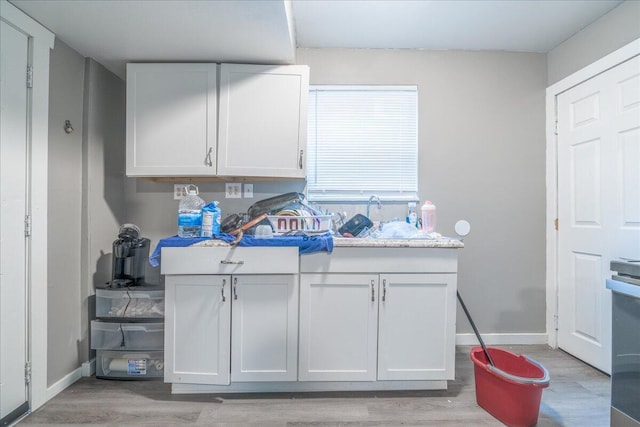 476 Graham St, Columbus, OH 43203 - kitchen featuring a sink, light wood-style floors, light countertops, white cabinetry, and baseboards