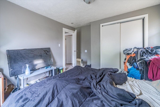 476 Graham St, Columbus, OH 43203 - bedroom with radiator heating unit, a closet, a textured ceiling, and carpet floors