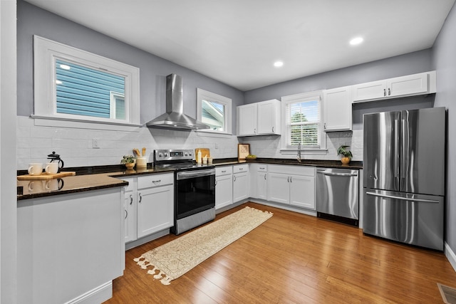 731 Siebert St, Columbus, OH 43206 - kitchen with stainless steel appliances, wall chimney exhaust hood, dark countertops, white cabinets, and backsplash