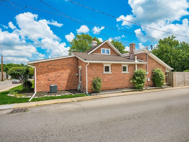 193 W Pearl St, West Jefferson, OH 43162 - view of home's exterior featuring a chimney, brick siding, cooling unit, and a shingled roof