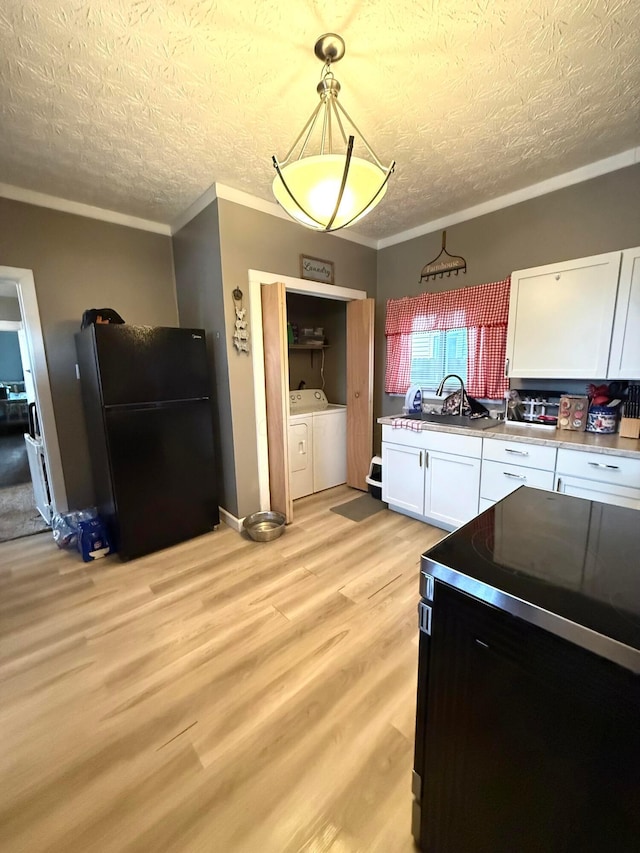 205 Walnut St, Circleville, OH 43113 - kitchen with freestanding refrigerator, washing machine and dryer, white cabinets, a textured ceiling, and light wood-type flooring