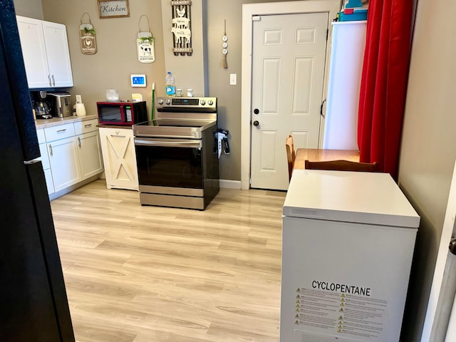 205 Walnut St, Circleville, OH 43113 - kitchen with stainless steel electric range, freestanding refrigerator, light wood-type flooring, white cabinetry, and light countertops