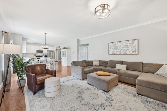 5952 Hampton Cors S, Hilliard, OH 43026 - living area featuring a chandelier, light wood-type flooring, ornamental molding, and baseboards