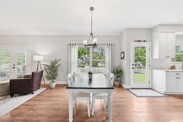 5952 Hampton Cors S, Hilliard, OH 43026 - dining space featuring a chandelier, baseboards, light wood-style flooring, crown molding, and french doors