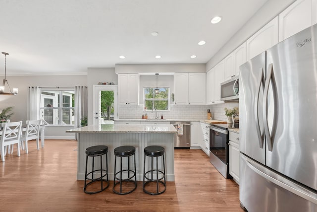 5952 Hampton Cors S, Hilliard, OH 43026 - kitchen with stainless steel appliances, a sink, a breakfast bar area, a kitchen island, and light stone countertops