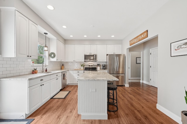 5952 Hampton Cors S, Hilliard, OH 43026 - kitchen with stainless steel appliances, a sink, a breakfast bar area, white cabinets, and tasteful backsplash