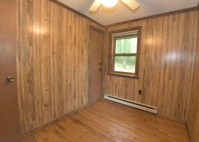 311 Chinook Ln, Sugar Grove, OH 43155 - spare room featuring a baseboard heating unit, wood finished floors, wood walls, and ceiling fan