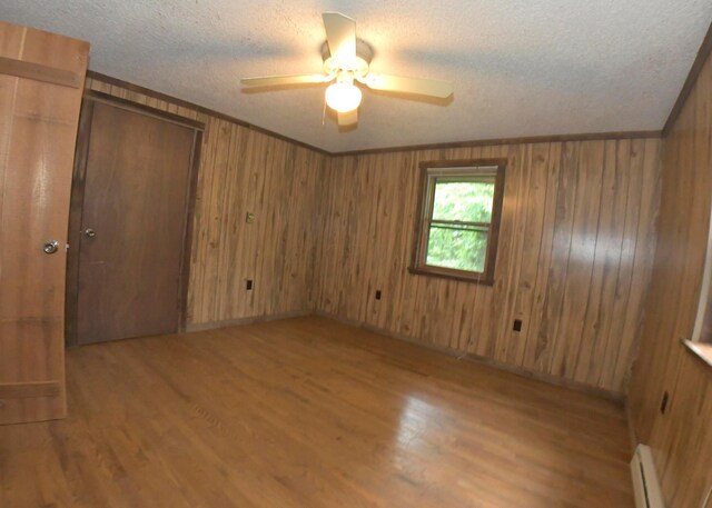 311 Chinook Ln, Sugar Grove, OH 43155 - spare room with baseboard heating, wood finished floors, a ceiling fan, a textured ceiling, and wood walls