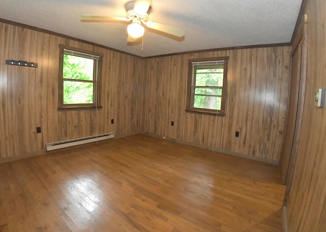 311 Chinook Ln, Sugar Grove, OH 43155 - unfurnished room featuring baseboard heating, a textured ceiling, wood finished floors, a ceiling fan, and wood walls