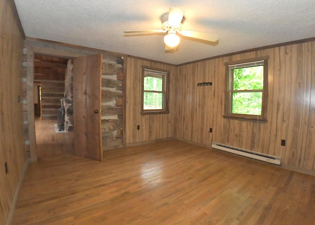 311 Chinook Ln, Sugar Grove, OH 43155 - empty room with baseboard heating, wood finished floors, wooden walls, a ceiling fan, and a textured ceiling