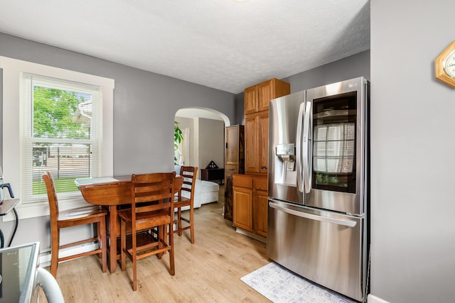 526 N Columbus St, Lancaster, OH 43130 - kitchen with stainless steel fridge with ice dispenser, arched walkways, light wood-type flooring, brown cabinetry, and a textured ceiling