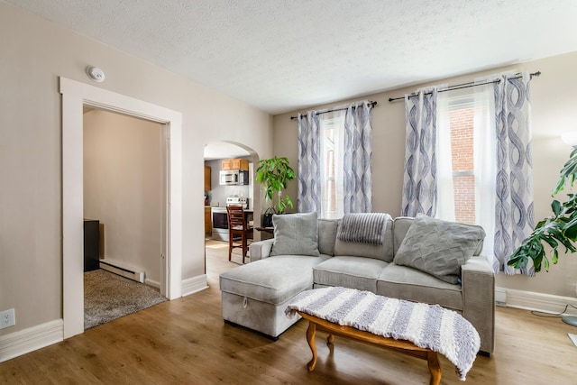 526 N Columbus St, Lancaster, OH 43130 - living area featuring arched walkways, a baseboard heating unit, light wood-type flooring, a textured ceiling, and baseboards