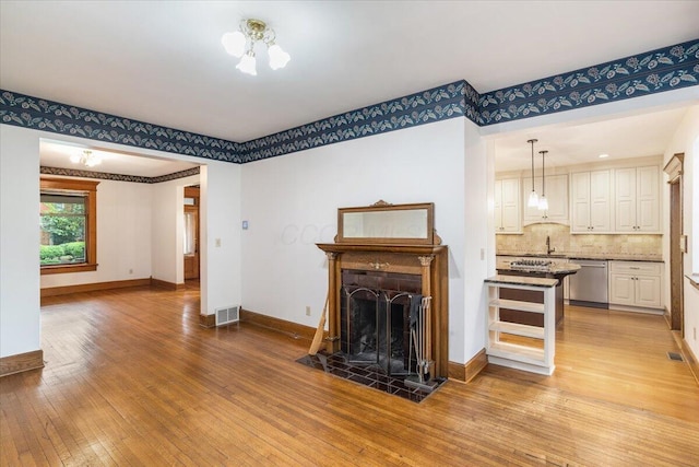 355 W 7th Ave, Columbus, OH 43201 - living area with light wood-style flooring, baseboards, a fireplace, and a chandelier