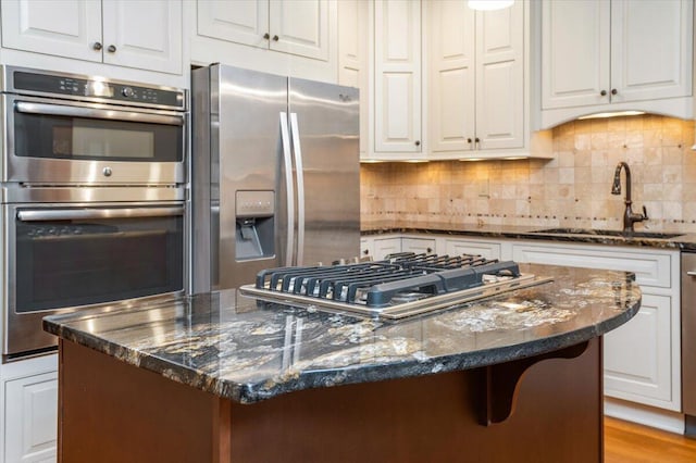 355 W 7th Ave, Columbus, OH 43201 - kitchen with appliances with stainless steel finishes, a sink, white cabinets, and a center island
