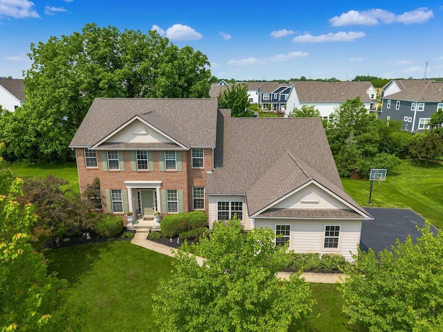 7019 Blakemore Ln, Dublin, OH 43016 - colonial-style house with a front yard, roof with shingles, and brick siding