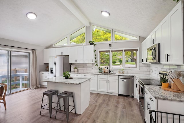 710 Cloverleaf Ct, Mansfield, OH 44904 - kitchen with stainless steel appliances, a sink, a breakfast bar, light wood-style floors, and a textured ceiling